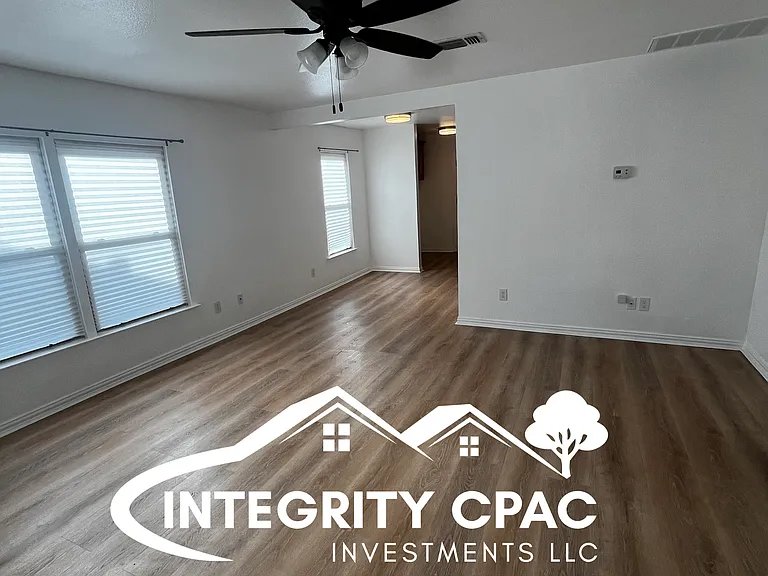 Spacious living area with white walls, ceiling fan, and wood floors, 1415 Lanius in Gainesville TX by Integrity CPAC